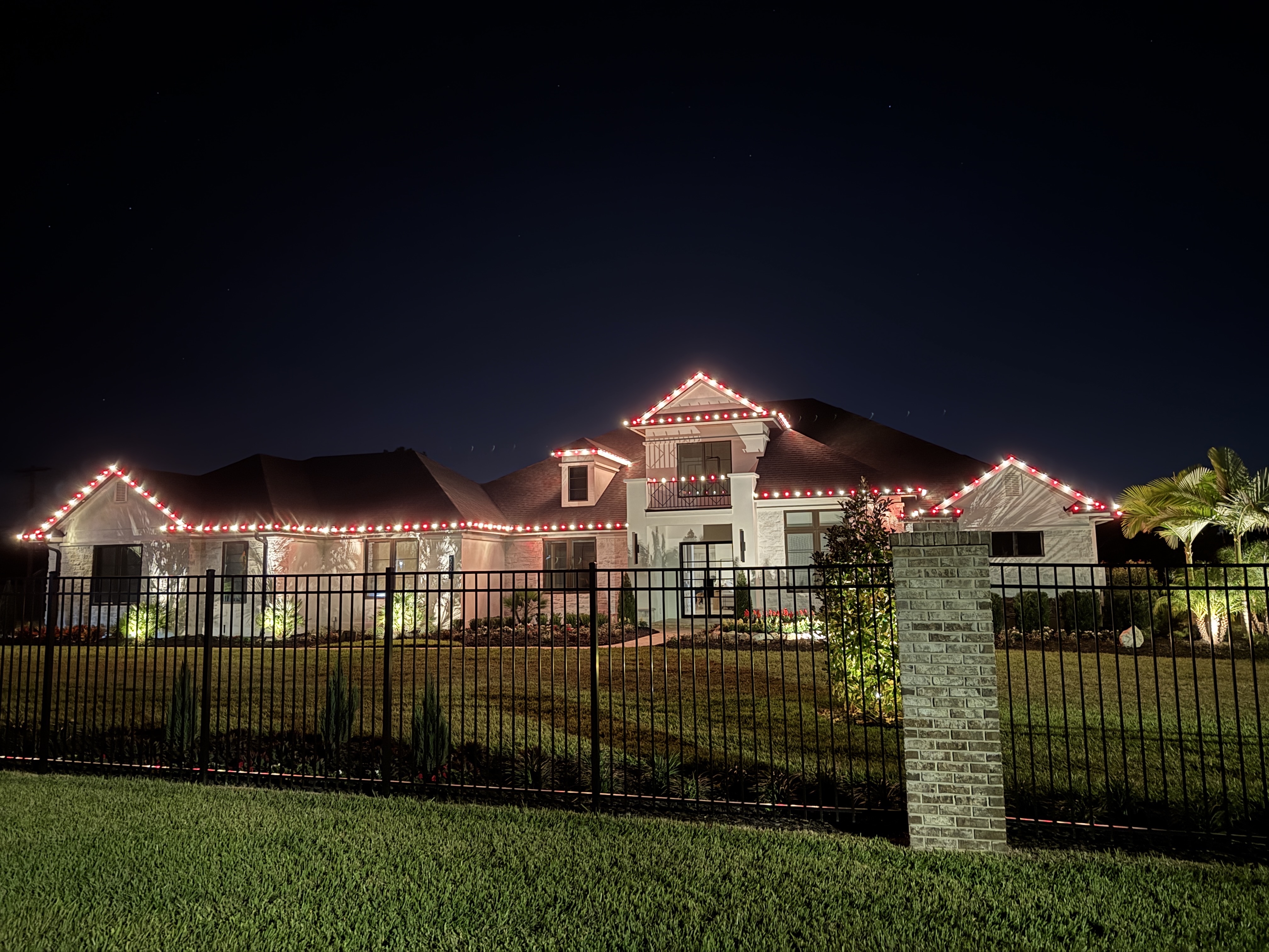 Front view of a home with alternating red and white roofline lights