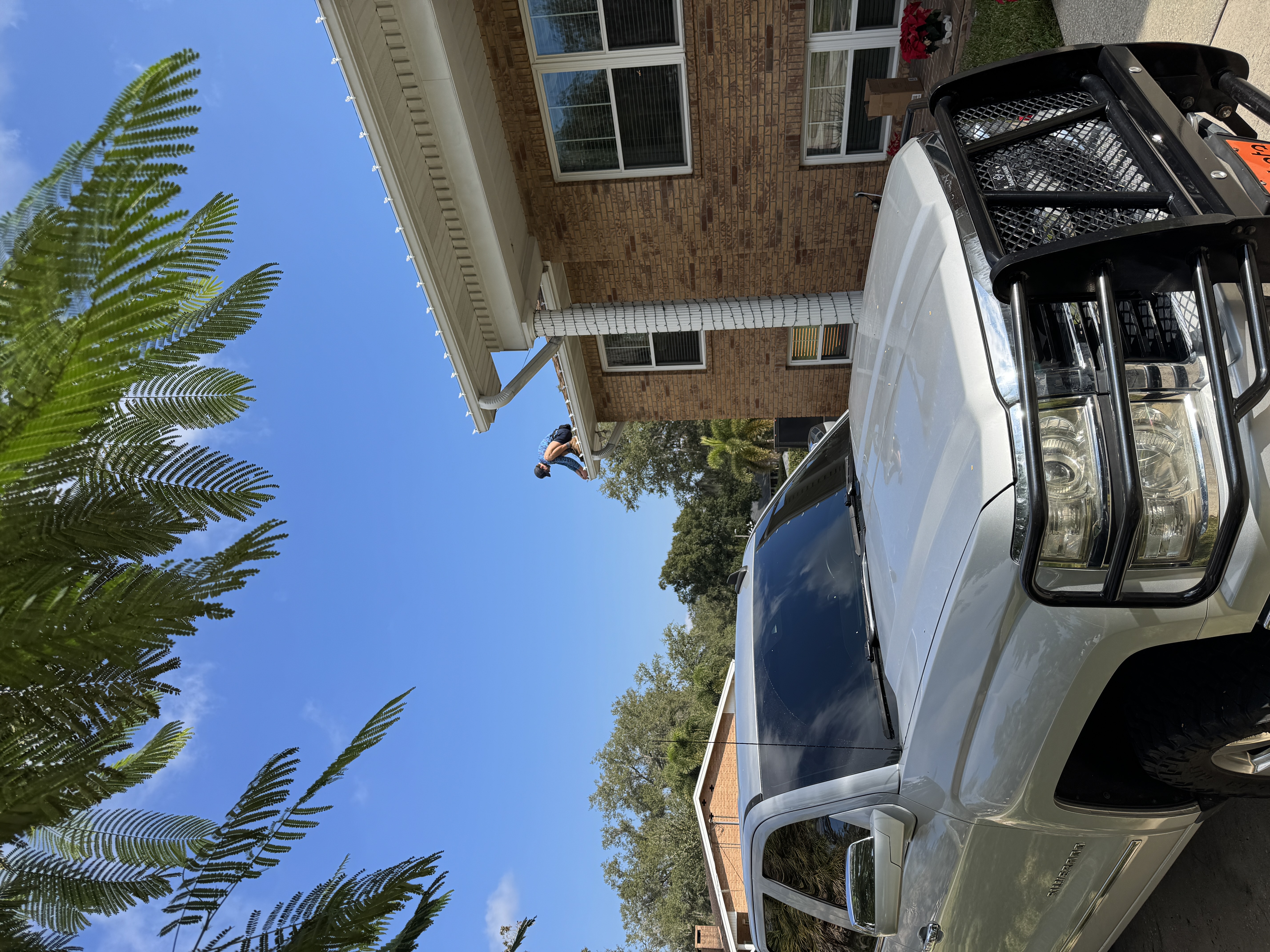 Team member installing roofline bulbs at a brick home during daylight